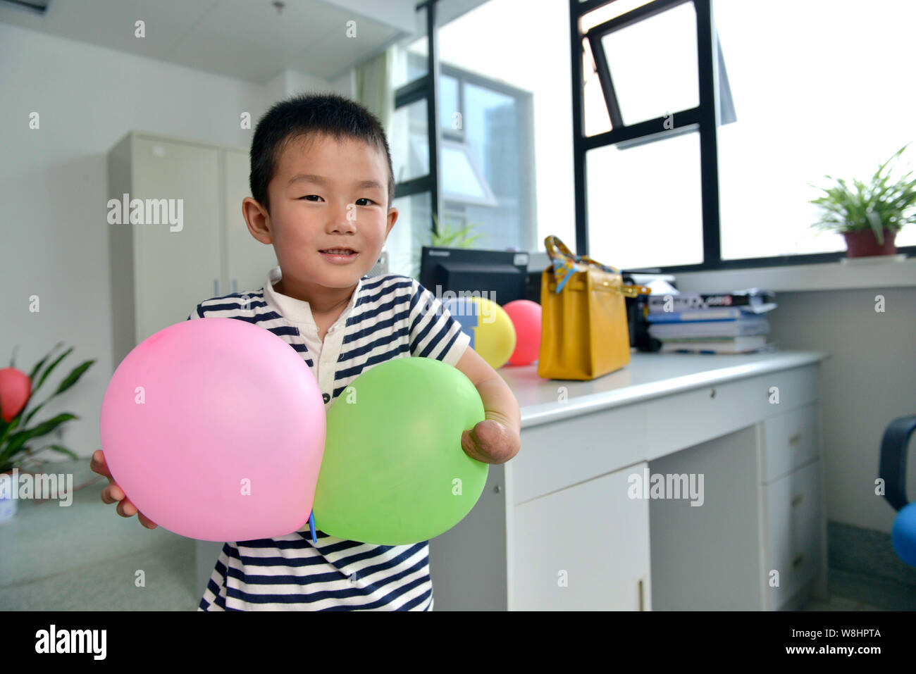 Sei-anno-vecchio Xiao Cheng che ha perso cinque dita della sua mano sinistra tiene di palloncini con le sue braccia a Wuhan Unione ospedale nella città di Wuhan, Cina centrale di Foto Stock