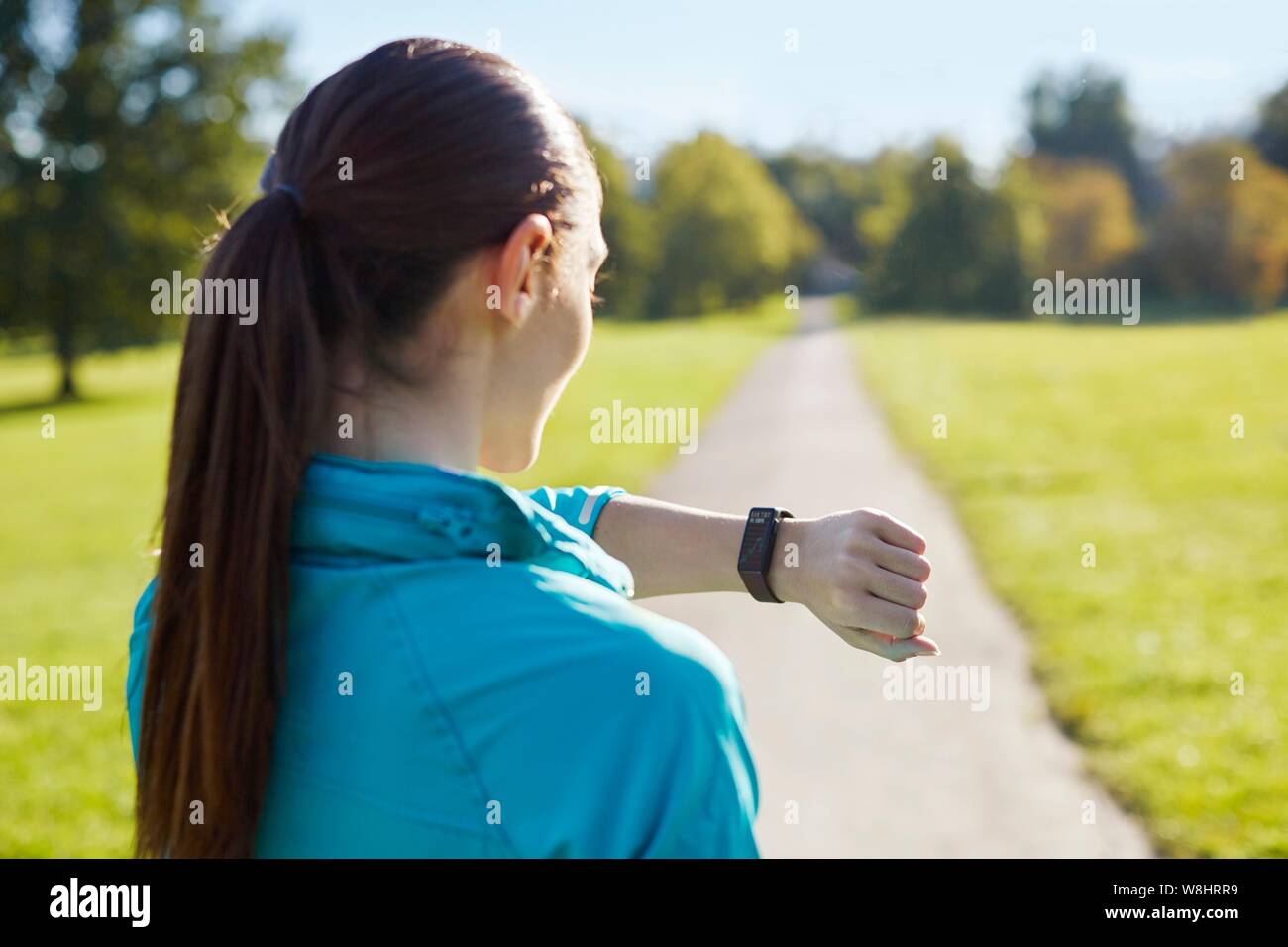 Giovane donna di indossare abbigliamento sportivo controllando il suo orologio. Foto Stock