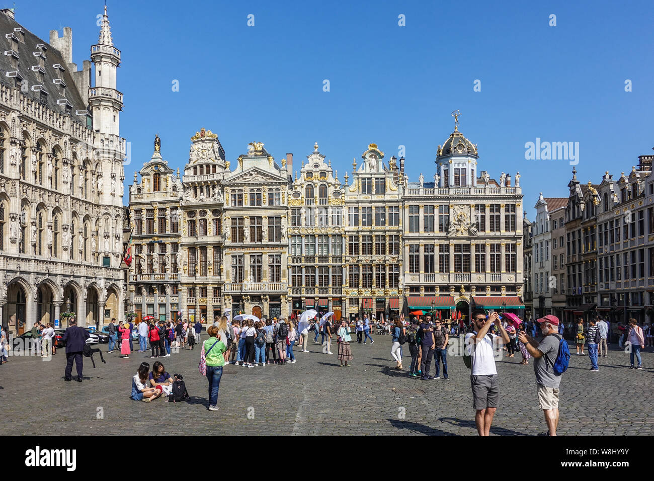 Bruxelles, Belgio - 22 Giugno 2019: Grand Place con turisti e beige e facciate di pietra, timpani e statue dorate del lato nord ovest contro il cielo blu. Ci Foto Stock