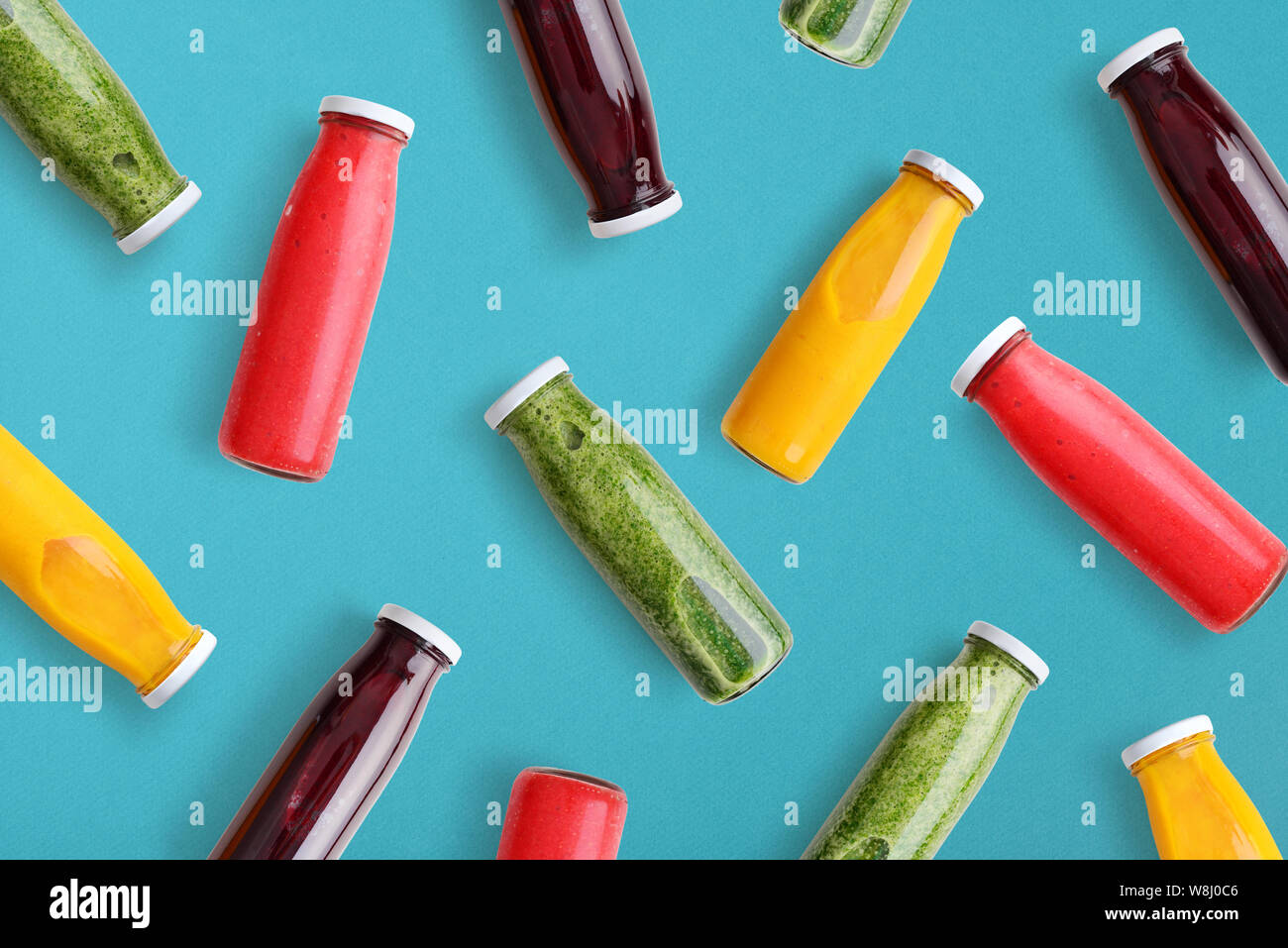 Frullati colorati in bottiglie di vetro su sfondo blu, vista dall'alto. Foto Stock
