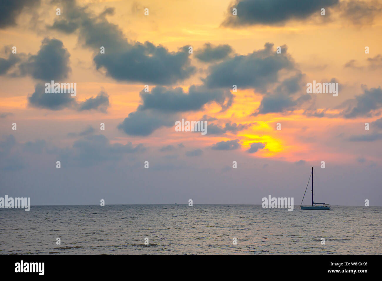 Yacht parcheggiato nel mare e il sole che tramonta dietro le nuvole di sera. Foto Stock