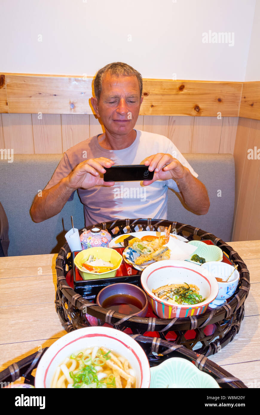 Un maschio estera tourist fotografando un menu fisso Giapponese presso un ristorante, Giappone Foto Stock