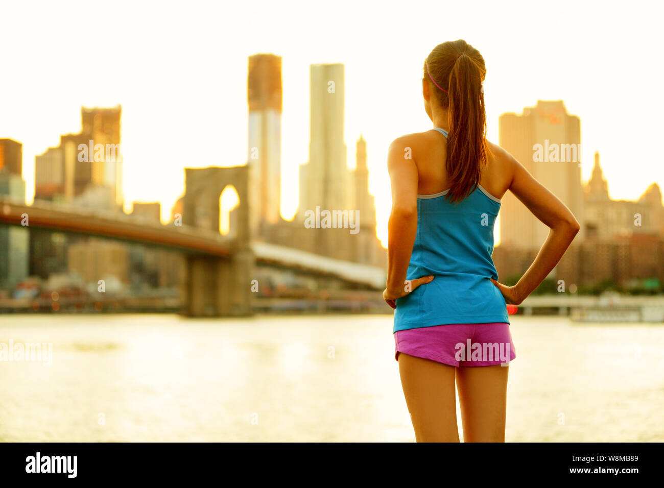 New York City attivo lo stile di vita di persone che vivono un urbano di vita attivo. Fitness donna sana runner rilassante dopo aver eseguito all'aperto godendo di vista del Ponte di Brooklyn. Foto Stock