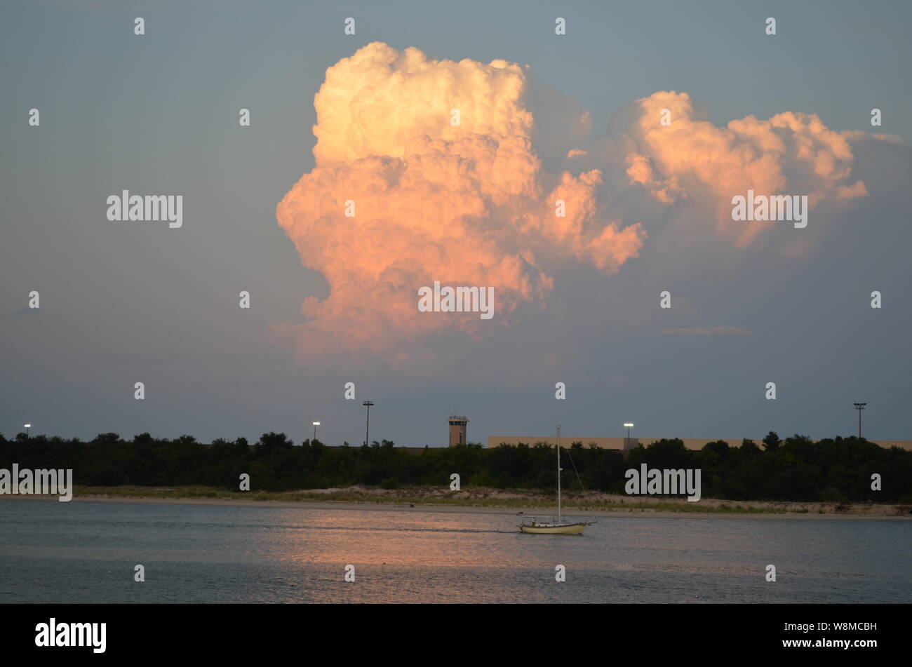 Arancione/rosa Cumulus tramonto le nubi sulla terra e acqua Foto Stock