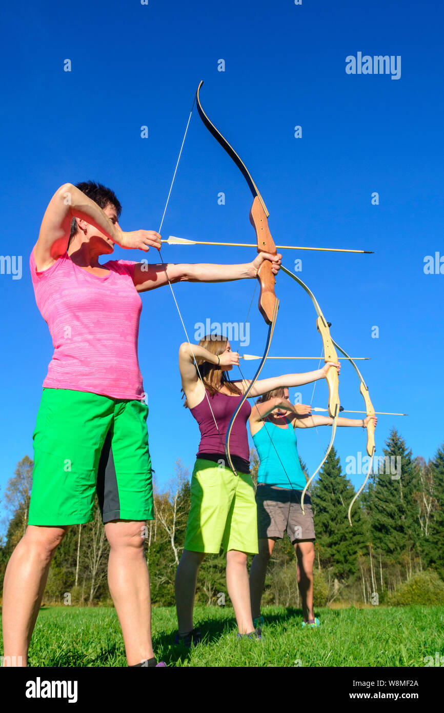 Tre donne facendo un concorso di tiro con l'arco nella natura Foto Stock