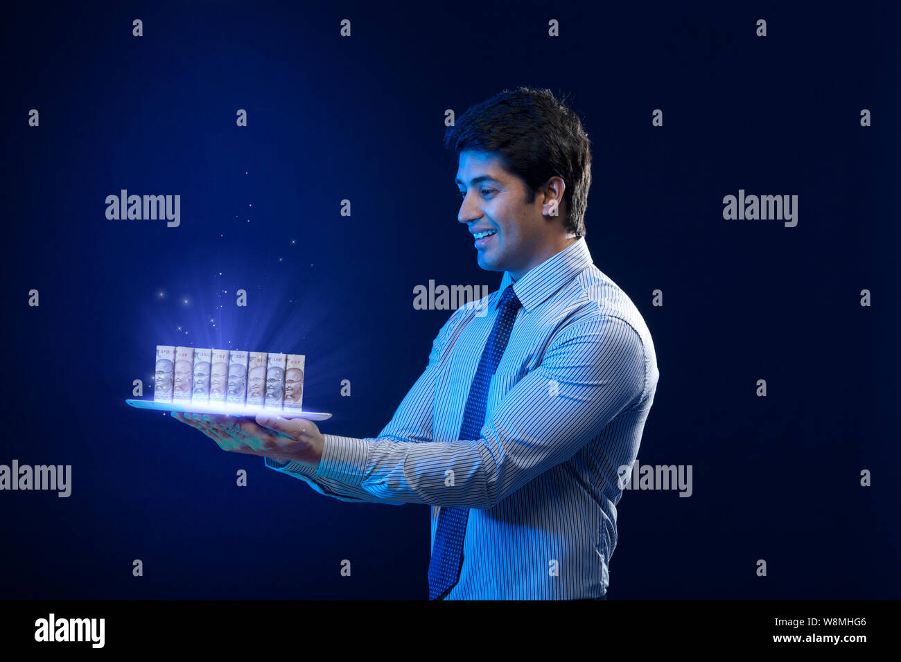 Emissione di luce dalla valuta cartacea arrotolata su tablet digitale Foto Stock