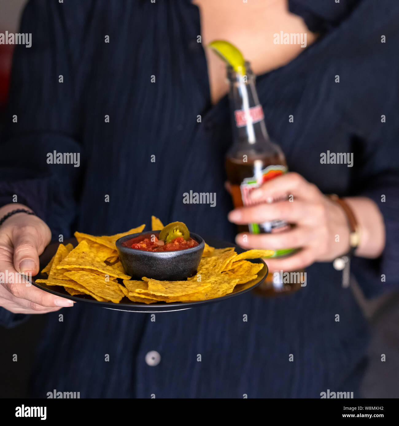 Mani tenendo la piastra messicano con nachos peperoncino rosso salsa e bottiglia di birra. Lifetyle street food sfondo . Foto Stock