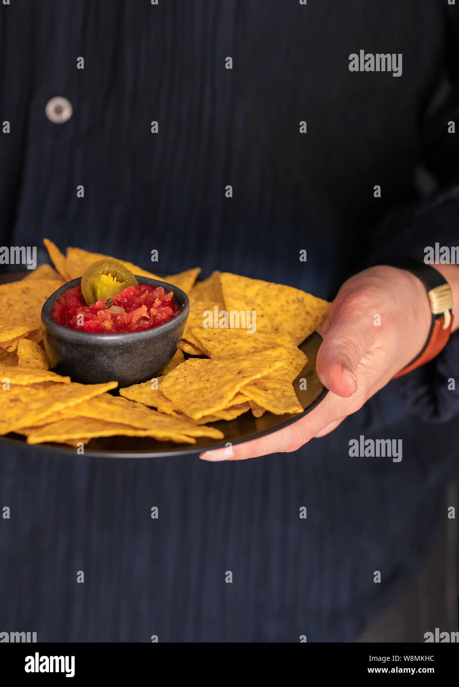 Mani tenendo la piastra messicano con nachos e il peperoncino rosso salsa.Lifetyle street food sfondo . Foto Stock