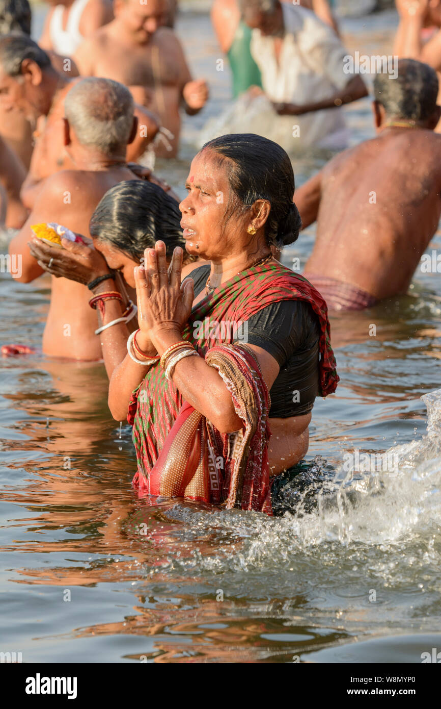 Un indiano donna Indù che indossa un sari offre preghiere agli dèi nel corso di un inizio di mattina rituale del bagno nel fiume Gange a Varanasi, India Foto Stock