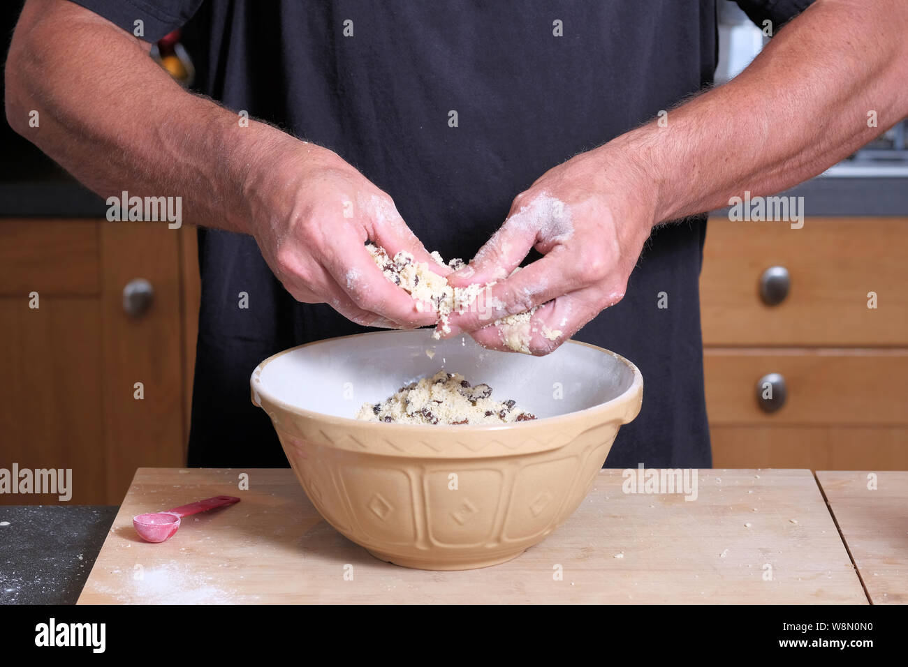 Un maschio di cuoco o baker mescolando un impasto in una ciotola di torta Foto Stock