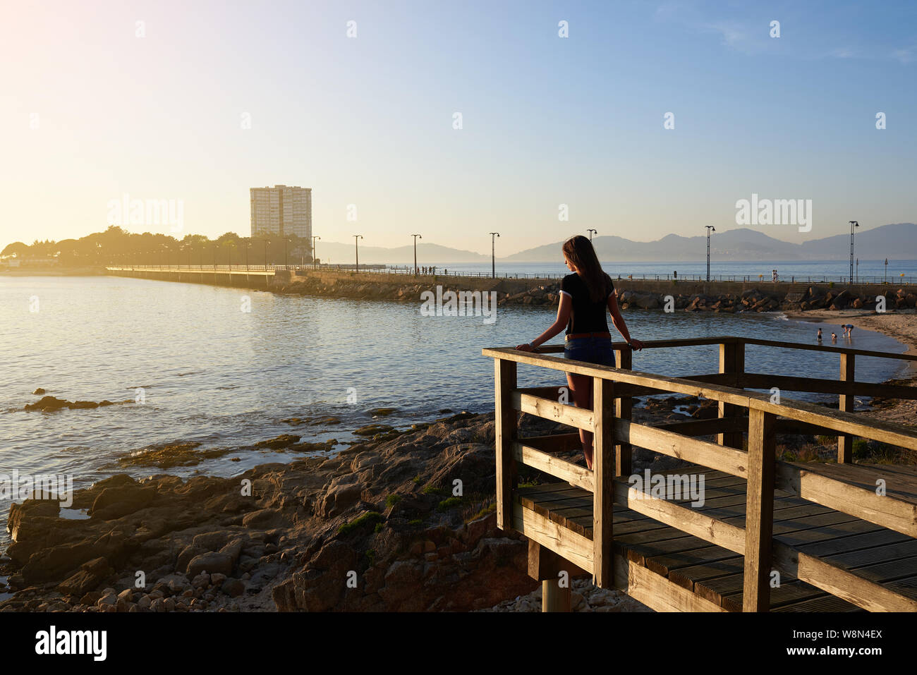 Giovane donna contemplando il mare da una struttura di legno a Vigo, in Spagna Foto Stock