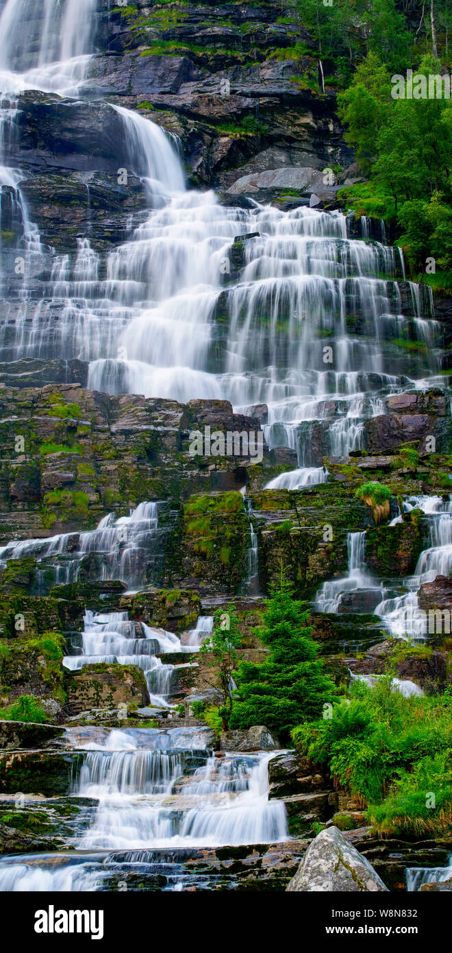 Noleggi verticale panorama di una cascata streaming su rocce con alberi e vegetazione, Norvegia Foto Stock