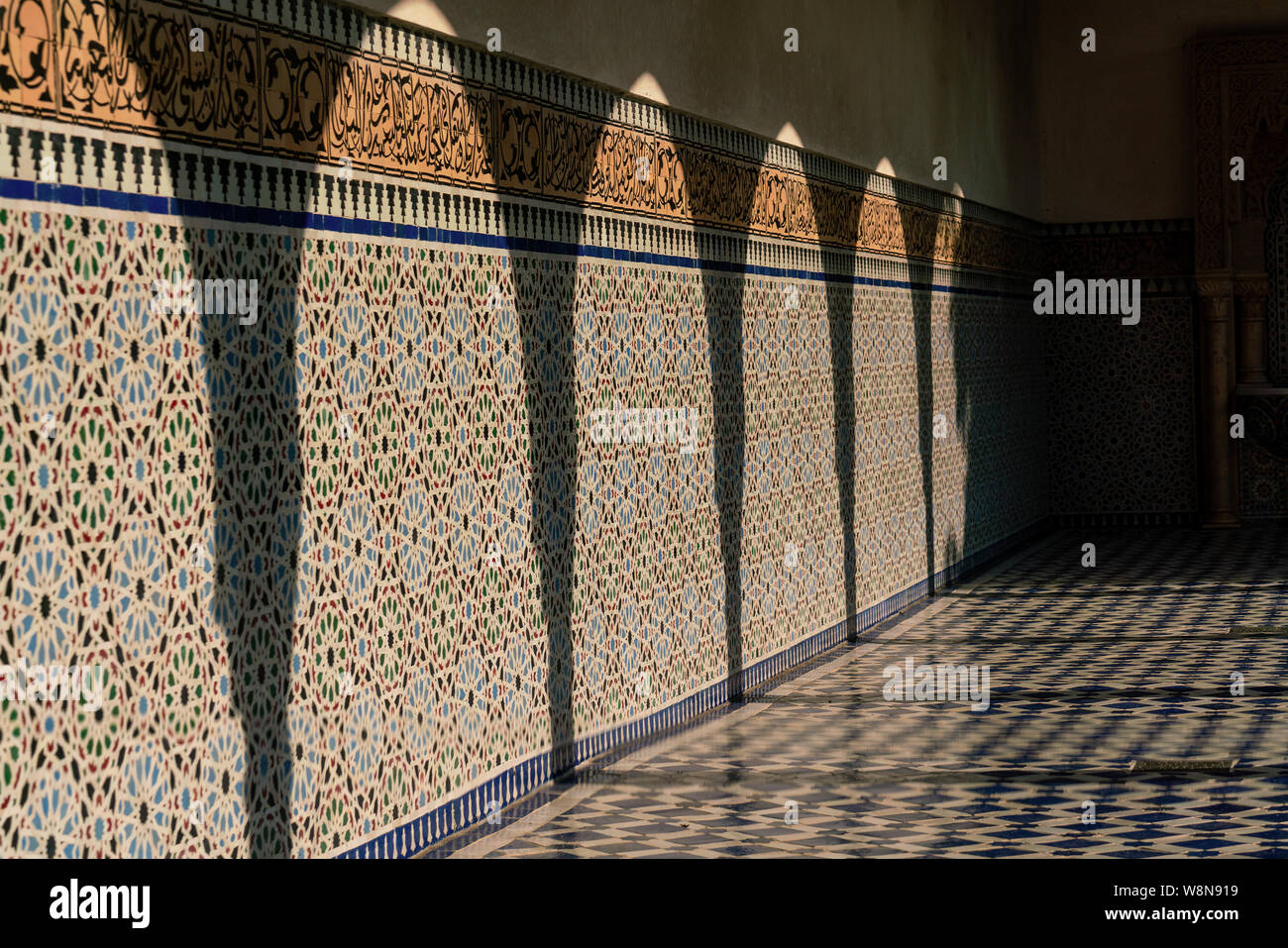 Le ombre dei pilastri su un mosaico di parete piastrellata in pieno sole Foto Stock