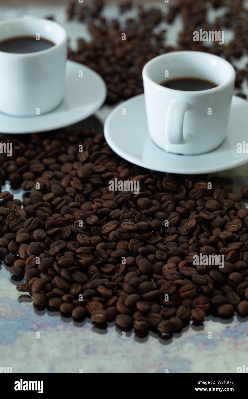 Nero caffè in tazze piccole. fuoriuscite di grani interi Foto Stock