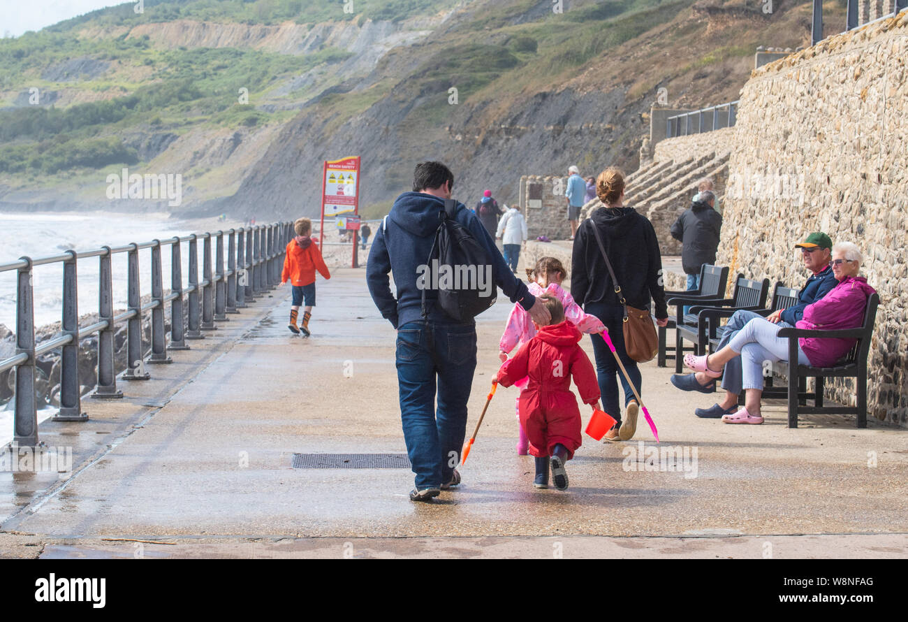Charmouth, Dorset, Regno Unito. Il 10 agosto 2019. Meteo REGNO UNITO: vacanzieri avventurarvi in un blustery giornata al villaggio sul mare di Charmouth come unseasonably strong a sud-ovest si snoda continuano ad impasto lungo la costa sud occidentale il sabato pomeriggio. Warmings giallo per il vento ad alta velocità sono stati rilasciati attraverso il Sud Ovest. Credito: Celia McMahon/Alamy Live News. Foto Stock