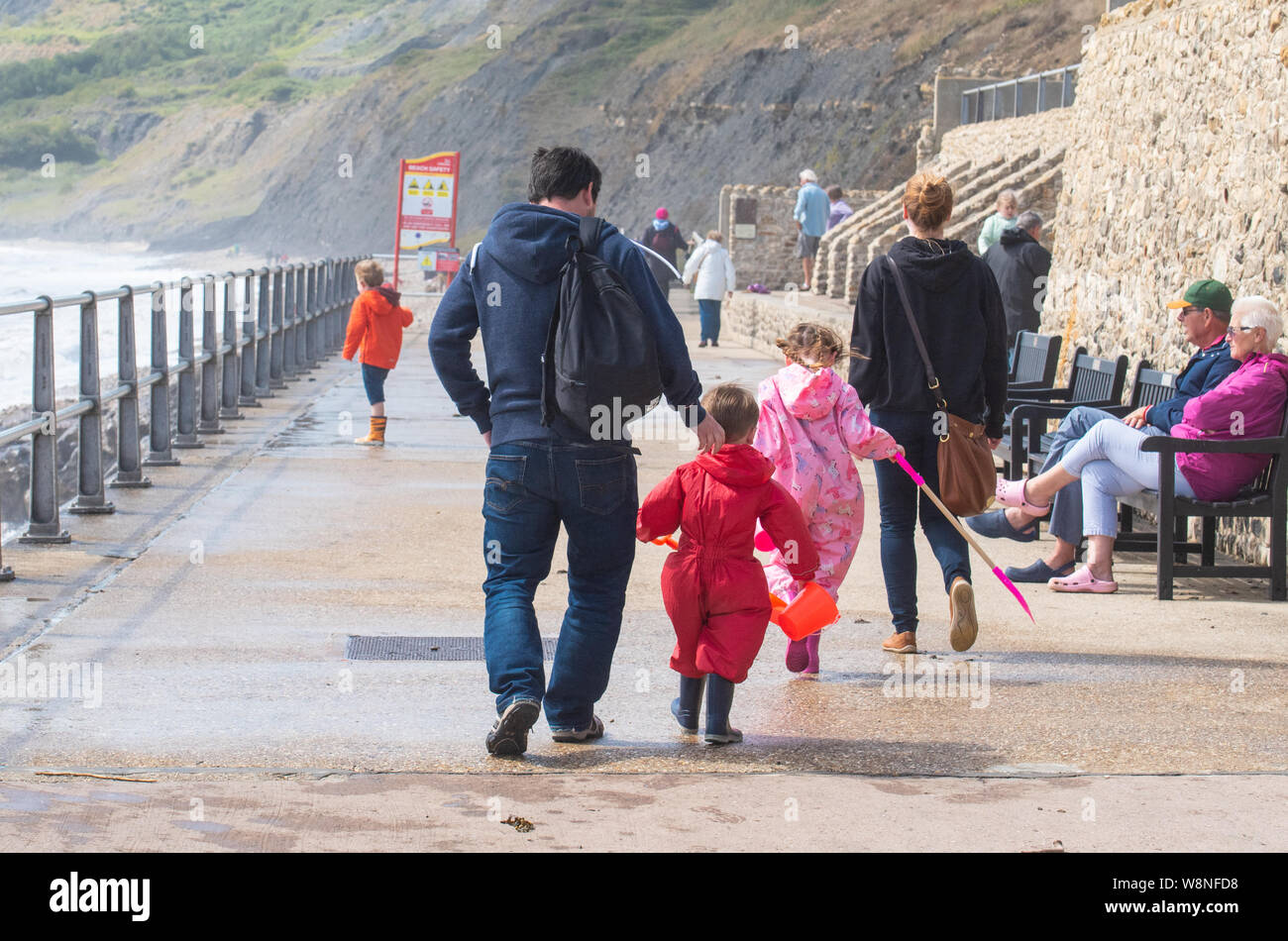 Charmouth, Dorset, Regno Unito. Il 10 agosto 2019. Meteo REGNO UNITO: vacanzieri avventurarvi in un blustery giornata al villaggio sul mare di Charmouth come unseasonably strong a sud-ovest si snoda continuano ad impasto lungo la costa sud occidentale il sabato pomeriggio. Warmings giallo per il vento ad alta velocità sono stati rilasciati attraverso il Sud Ovest. Credito: Celia McMahon/Alamy Live News. Foto Stock