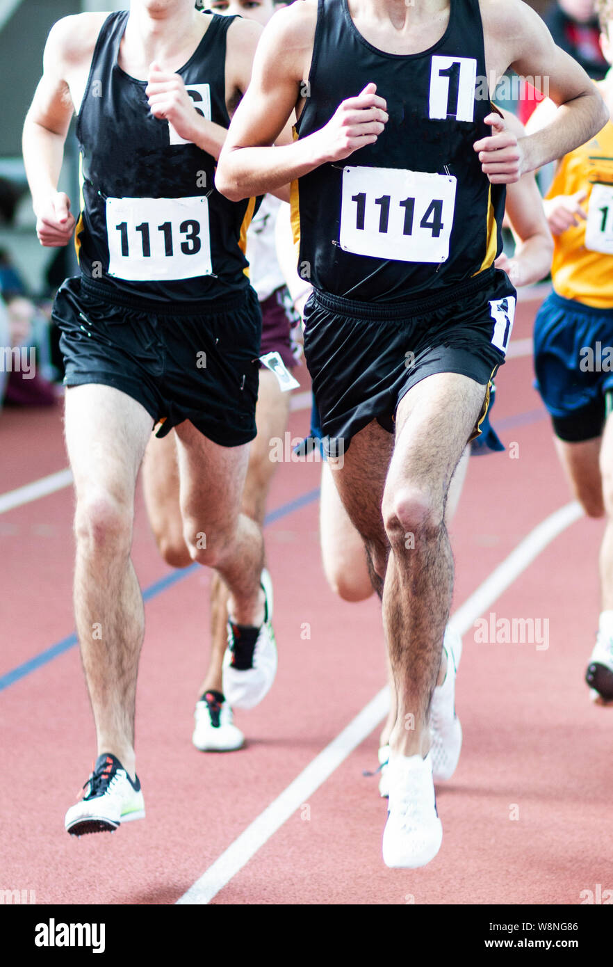 Due ragazzi di liceo dallo stesso team leader sono il miglio su una pista coperta durante una gara. Foto Stock
