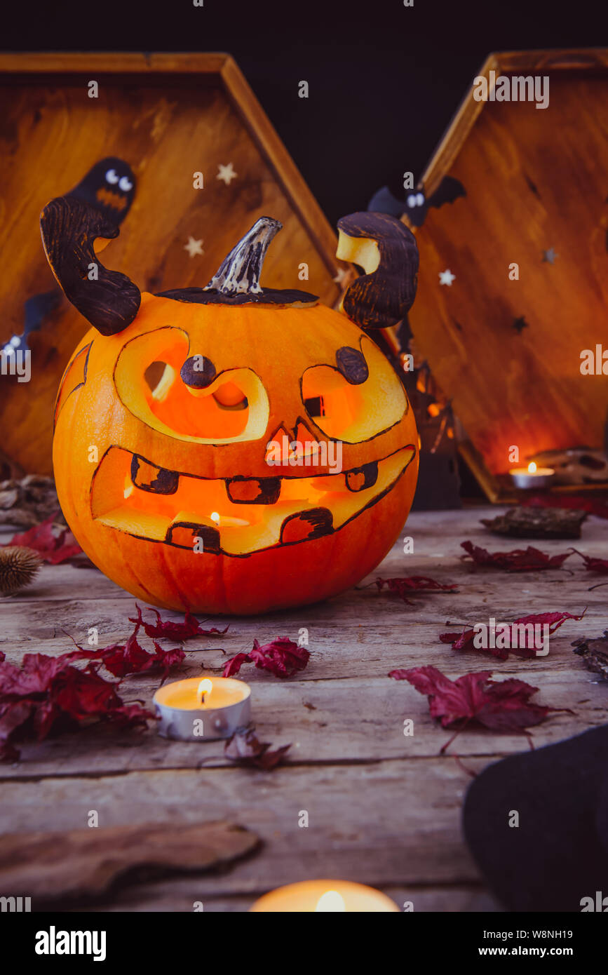 Scolpite di zucca e altri simboli di Halloween su sfondo di legno. Zucca di Halloween jack testa lanterna con scary male facce. Spooky Concetto di vacanza. Foto Stock