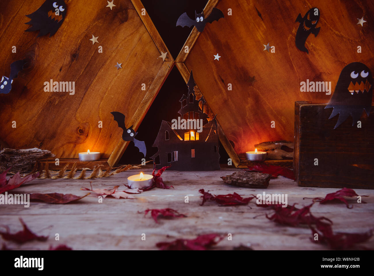 Halloween Concetto di vacanza . Illuminazione di sagome di carta del vecchio castello, fantasmi, strega, pipistrelli, candele su sfondo di legno con autunno foglie secche. Sp Foto Stock