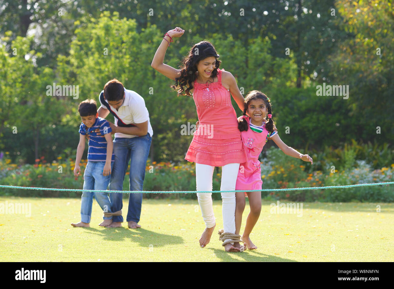 Famiglia che gioca a tre zampe in un giardino Foto Stock