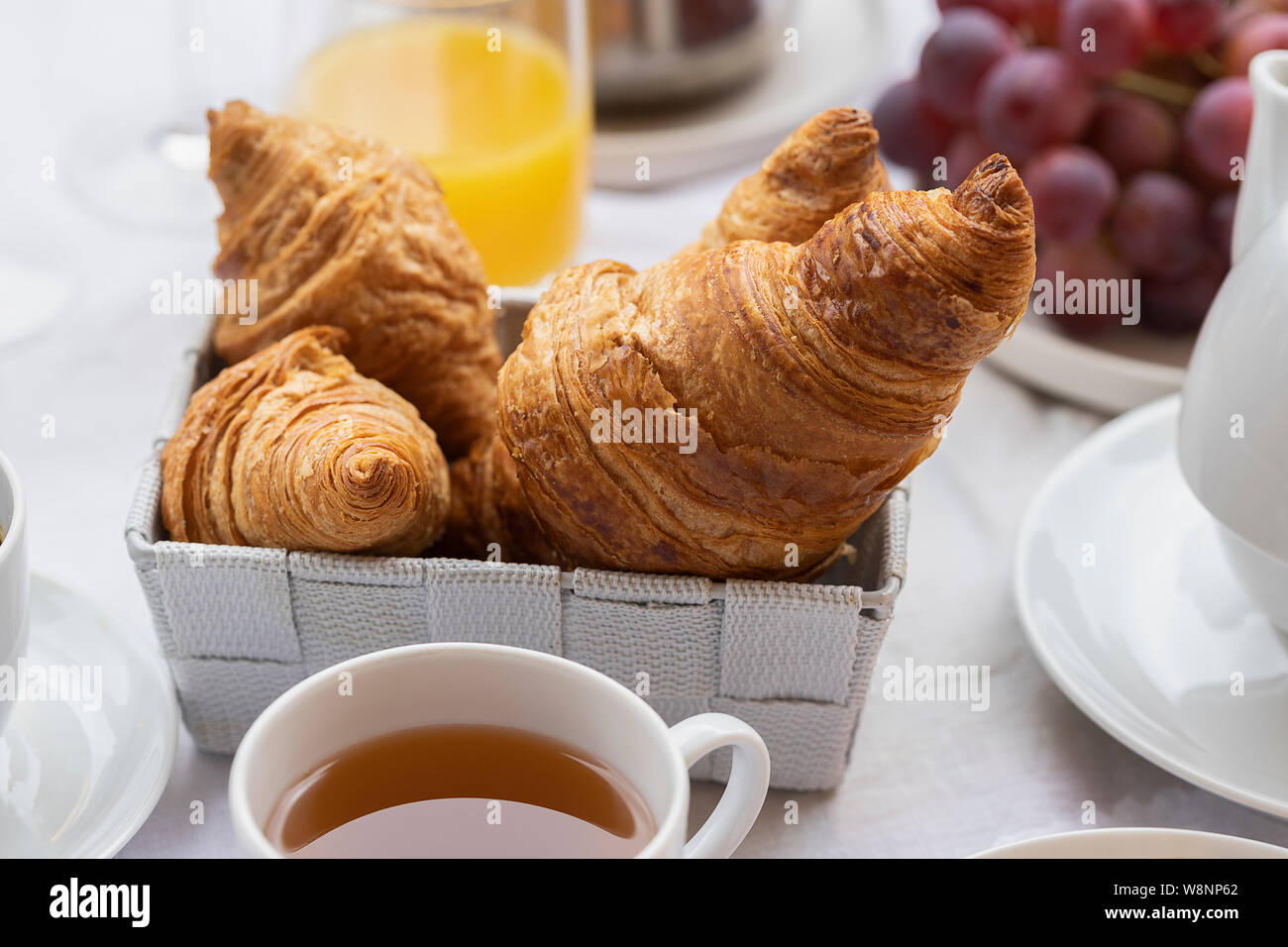 Prima colazione francese, bevanda calda e cornetti, frutta, succo d'arancia. Buona mattina concetto dello sfondo. Foto Stock