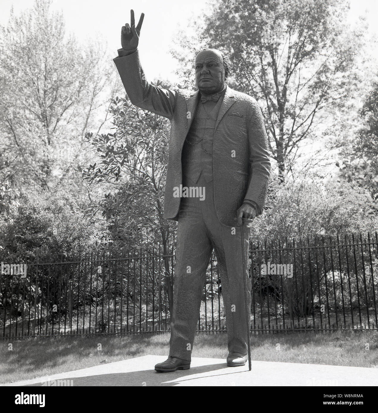 Stati Uniti d'America,1960s, una fotografia da J Allan contanti che mostra la scultura in bronzo di William M. McVey a WW2 Briitish Primo Ministro Sir Winston Churchill al di fuori dell'Ambasciata britannica a Washington DC. La statua mostra Churchill usando il suo famoso gesto a mano, il segno V, V per la vittoria di campagna di WW2. Foto Stock