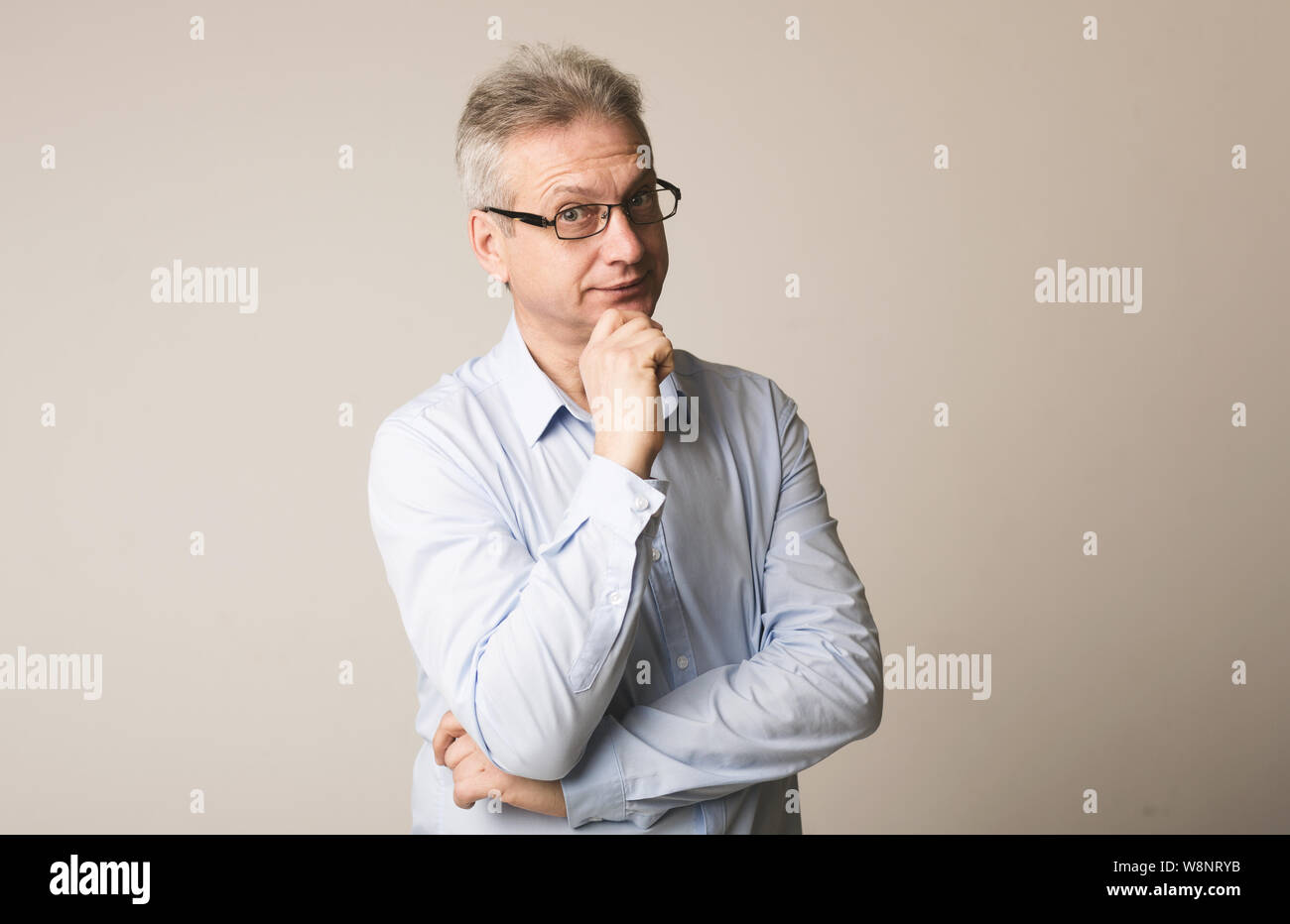 Successo imprenditore maturo guardando la fotocamera e sfondo grigio Foto Stock