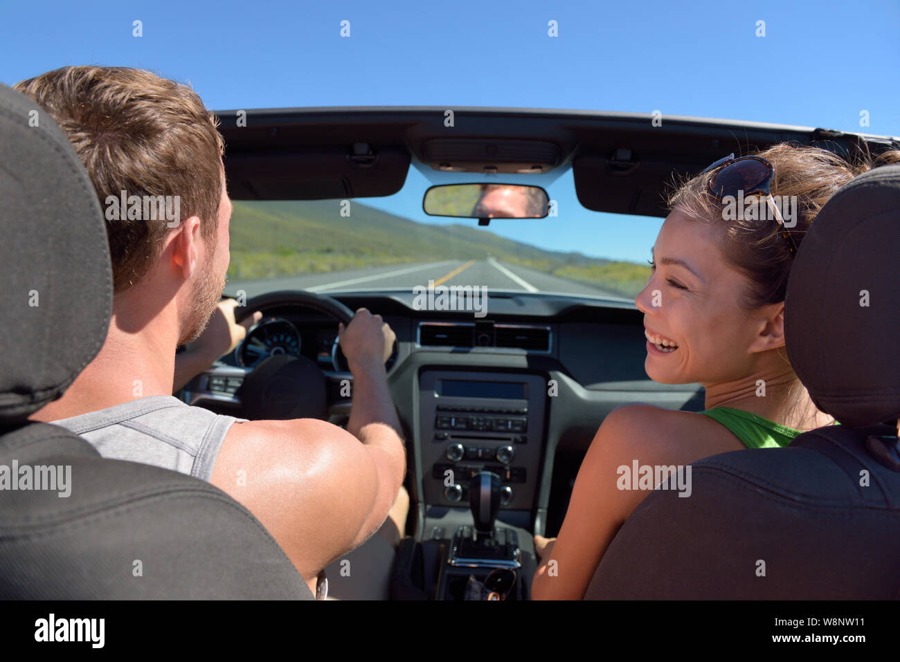 Giovane guida auto sulla strada viaggio vacanza in convertibile. Giovane coppia romantica sul viaggio vacanze vacanza. Driver uomo dietro il volante. Foto Stock