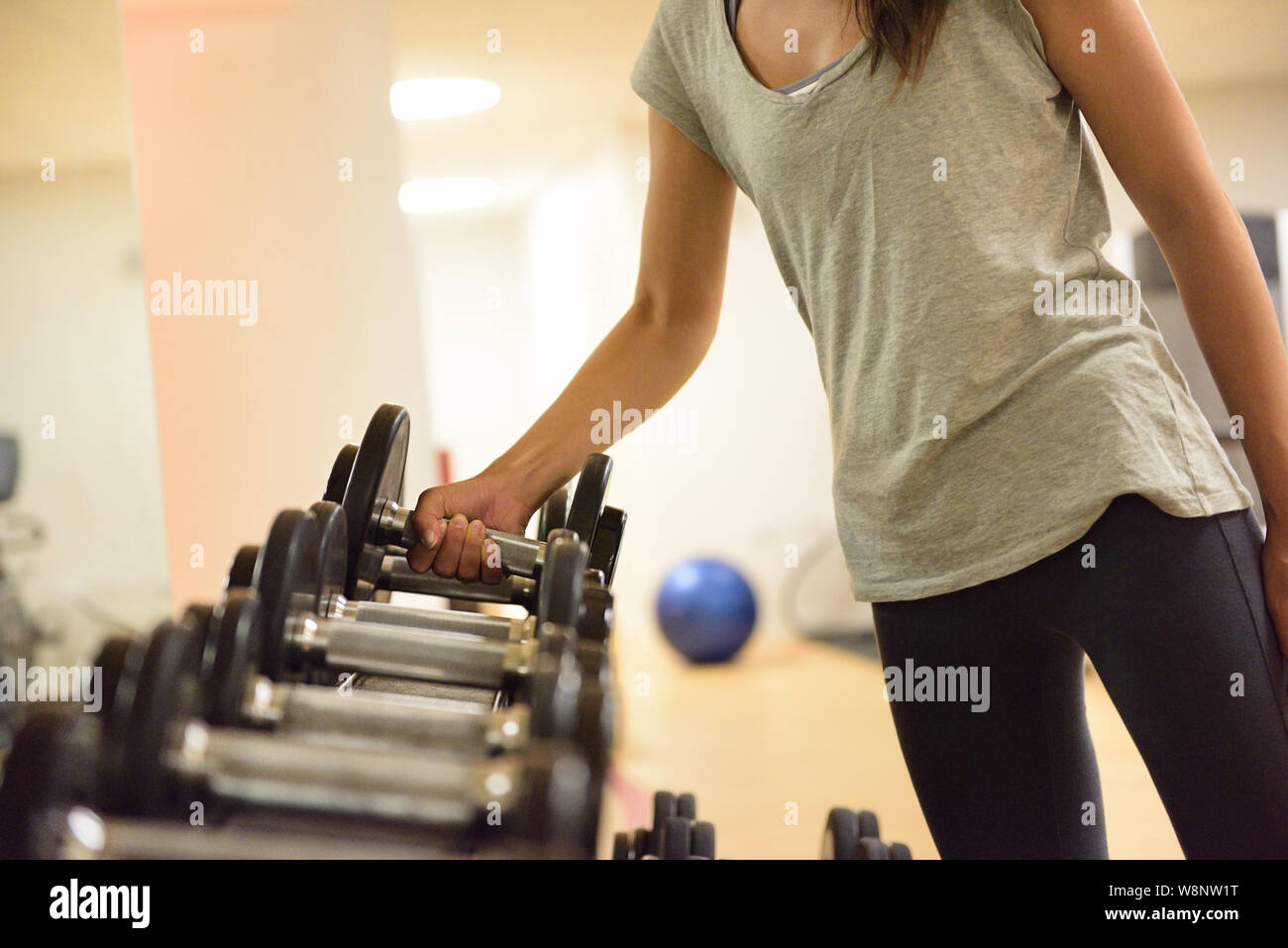 Palestra donna training di forza di sollevamento pesi a manubrio ottenere pronto per l'esercizio allenamento. Femmina ragazza fitness esercizio piscina nel centro fitness. Montare la bella gara di misto asiatico modello caucasico. Foto Stock