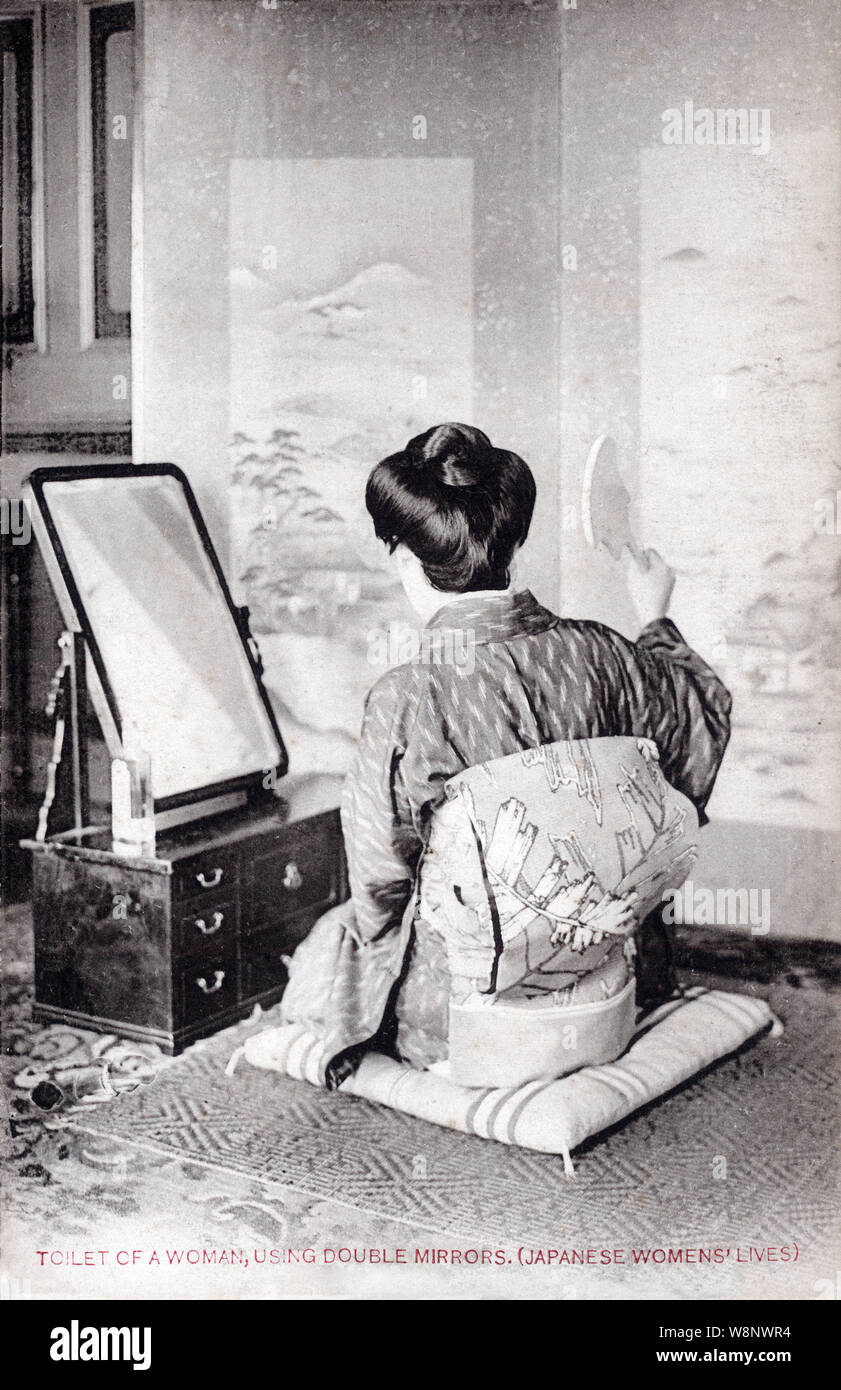 [ 1920s Giappone - donna giapponese con specchi ] - Una donna sta esaminando i suoi capelli con specchi awasekagami (合わせ鏡), uno di loro strategicamente collocato su un keshoubako (化粧箱, make-up box). Quando non è in uso, gli specchi sono sempre stati coperti con tessili. Testo originale: "Gabinetto di una donna, utilizzando specchi doppi. (Giapponese la vita delle donne)' del xx secolo cartolina vintage. Foto Stock