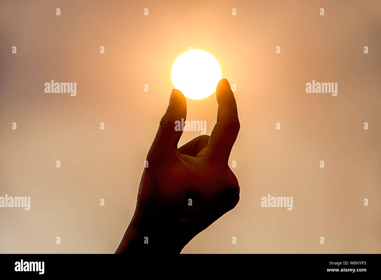 Una immagine concettuale di trattenere il sole in due dita. Foto Stock