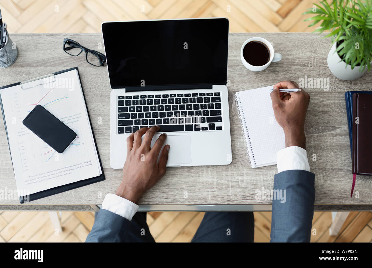 Imprenditore nero lavorando sul suo laptop seduto sul posto di lavoro Foto Stock