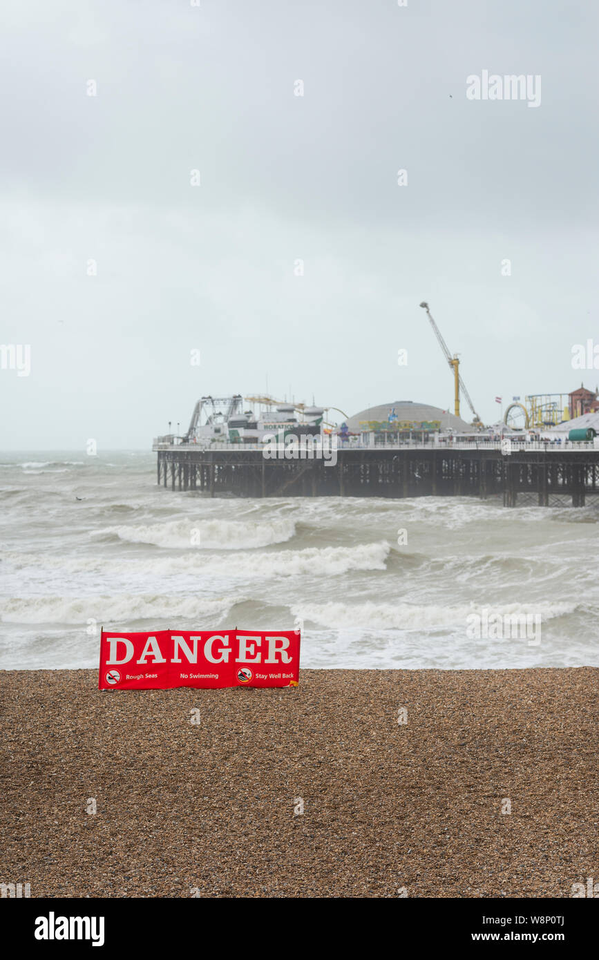 Brighton, Inghilterra, Regno Unito. 10 Ago, 2019. Brighton, East Sussex. Il 10 agosto 2019. Regno Unito Meteo. Una banda di bassa pressione si sta diffondendo in tutto il paese portando i venti forti e grandi onde che si infrangono a Brighton Seafront, come spettatori guarda su e ancora provare a godersi la spiaggia in questo unseasonably e avverse condizioni atmosferiche. Nel Regno Unito gli avvisi meteo per vento sono stati rilasciati in tutto il paese dalla Met Office, con raffiche fino a 60mph sulla costa sud. Credito: Francesca Moore/Alamy Live News Foto Stock