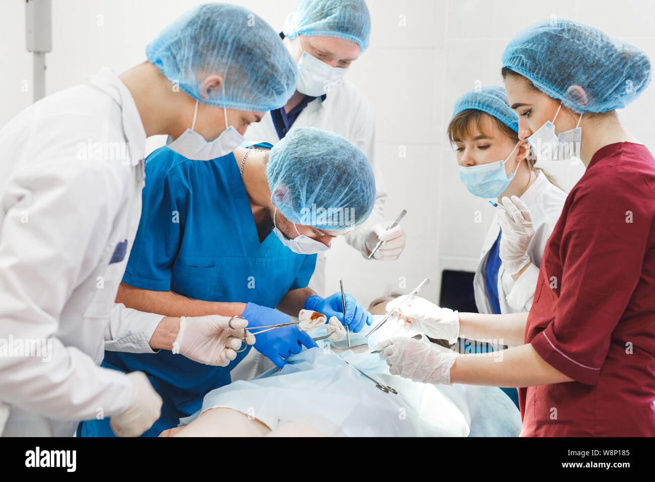 Gruppo di chirurghi al lavoro che operano in sala operatoria. Medicina di rianimazione team indossando maschere di protezione Foto Stock