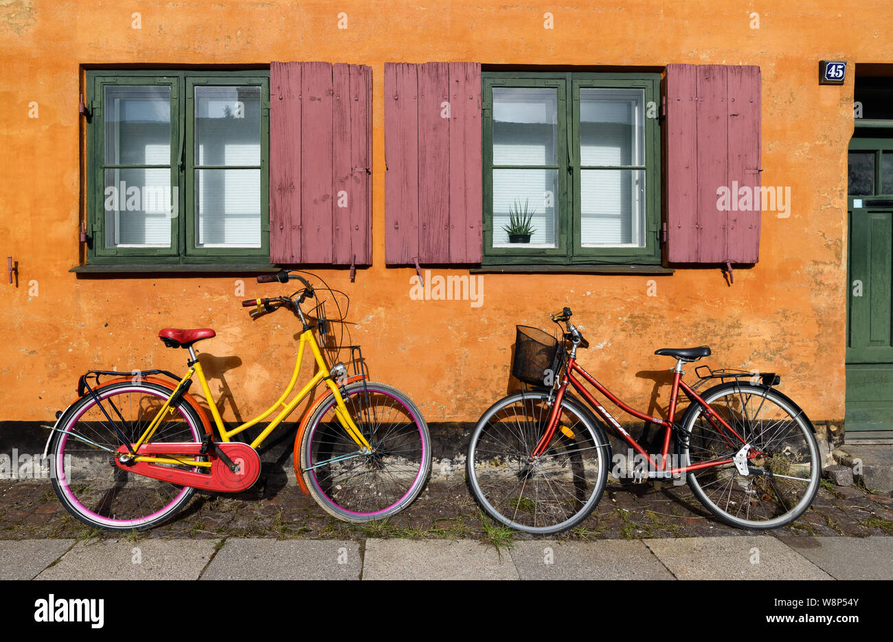 Le biciclette di fronte a una casa arancione facace in Nyboder (fila storica casa distretto della ex caserma navale a Copenaghen, Danimarca). Foto Stock