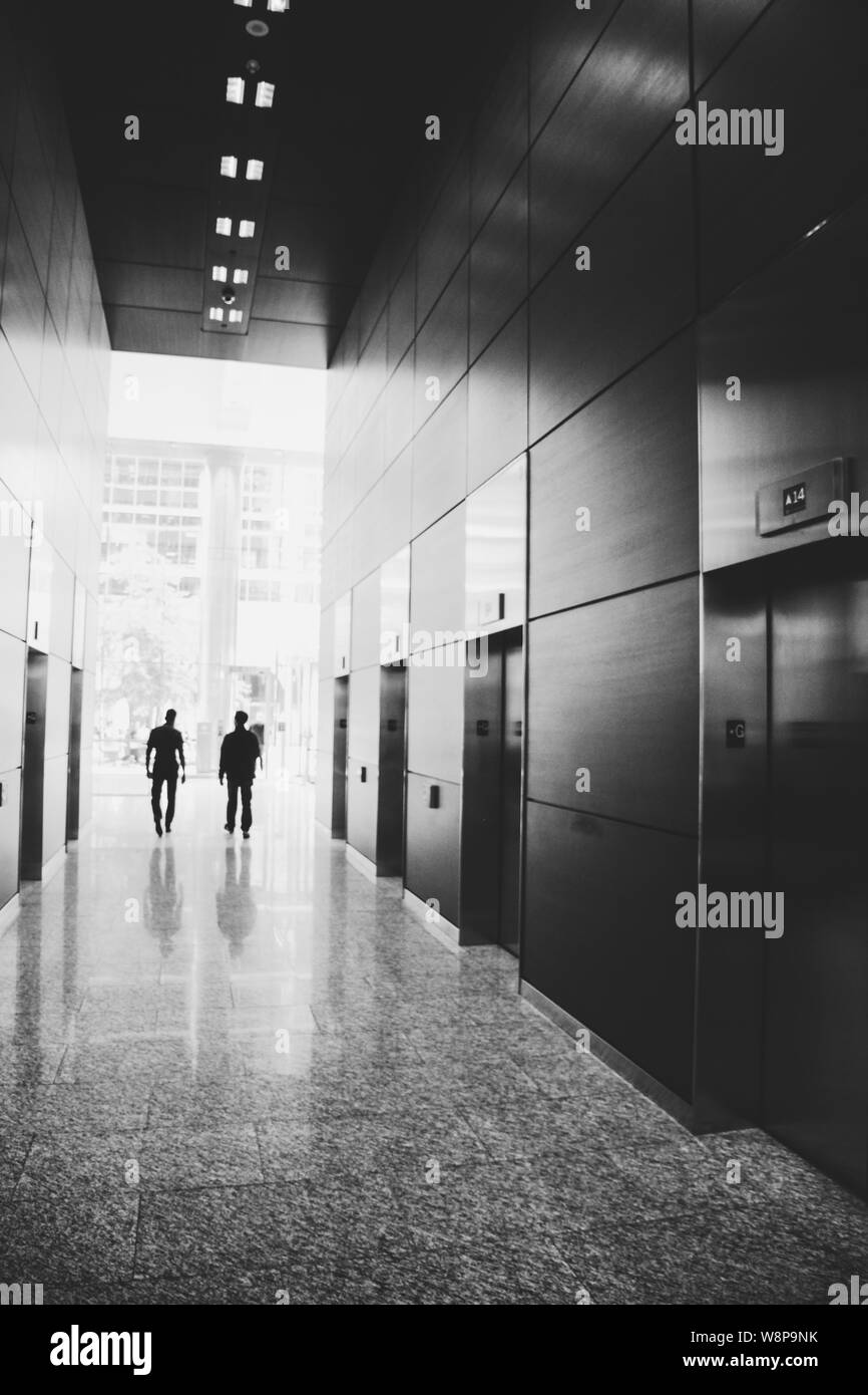 La gente di affari a piedi da ascensori in bianco e nero Foto Stock