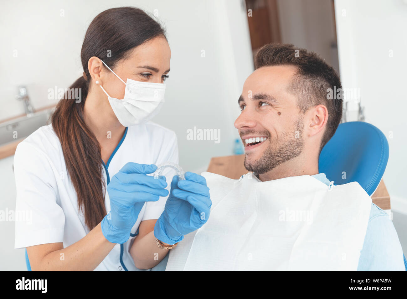 Dentista mostra invisibile allineatore di bretelle. Consultazione dentale in una clinica ortodontica Foto Stock