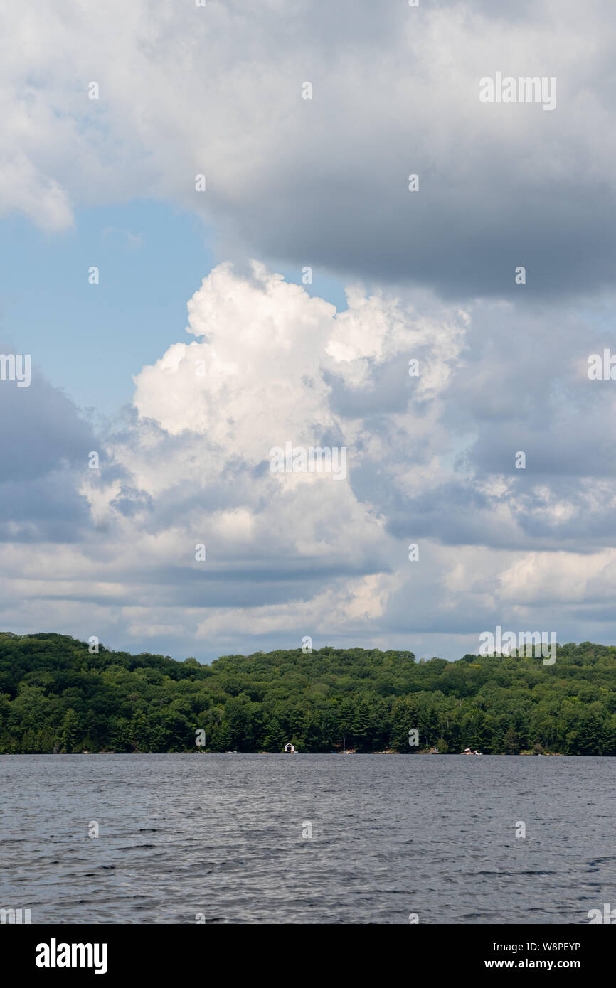 Cielo blu a forma di cuore, attraverso dense di bianco e grigio nuvole sopra un lago in un assolato pomeriggio estivo in Ontario. Foto Stock