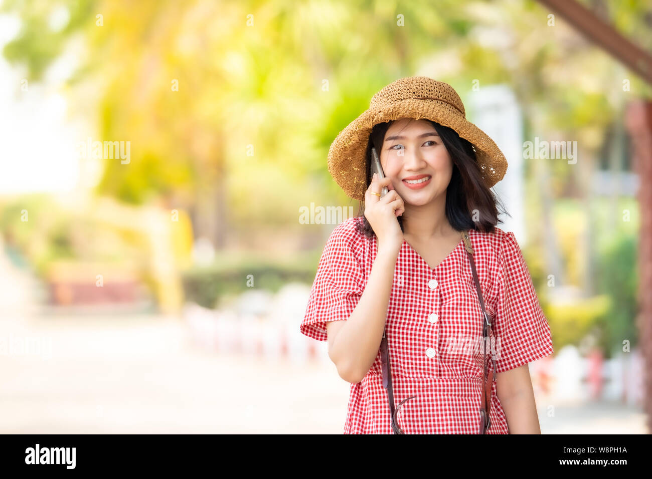 Donne asiatiche turisti utilizzare smart phone e sorridente brillantemente presso la stazione ferroviaria. Foto Stock