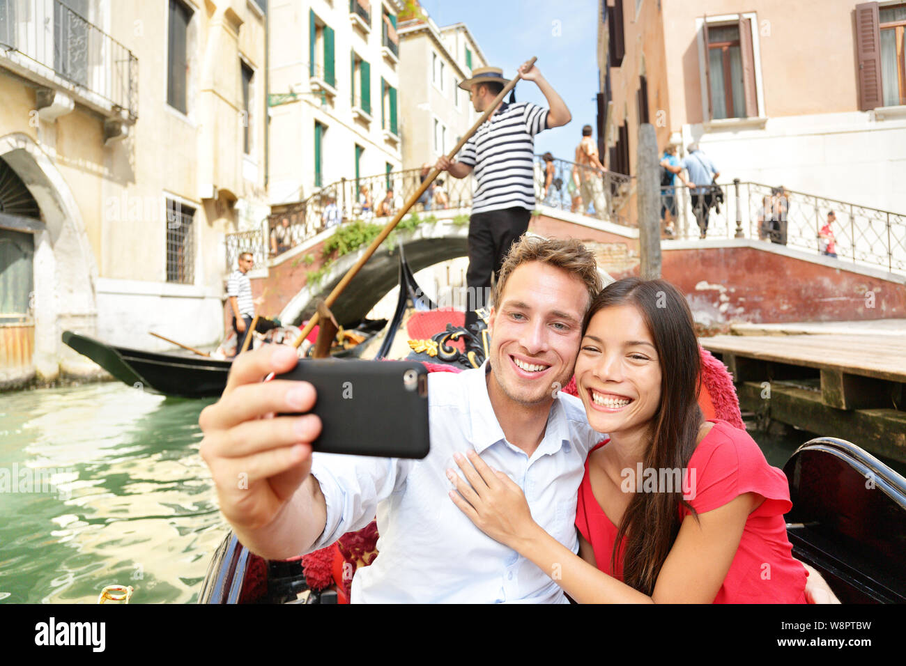 Selfie paio di scattare una foto in gondola a Venezia travel vacation. Gli amanti della bella su un romantico giro in barca attraverso i canali veneziani tenendo Self-portrait foto con lo smartphone durante la vacanza. Foto Stock