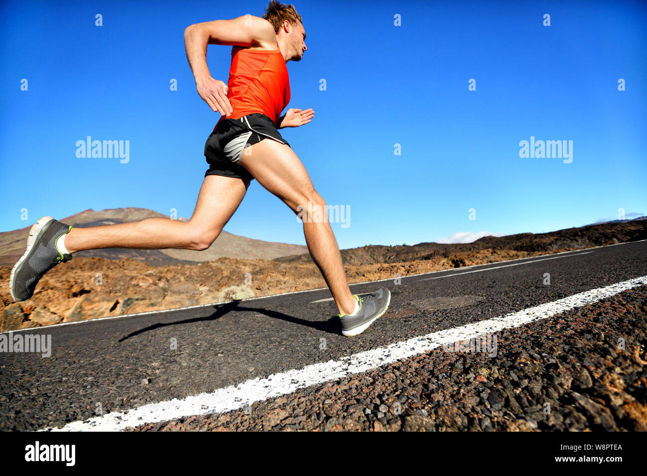 Runner running man in volata per il successo su run. Atleta maschio runner formazione a velocità alta. Muscolare di montare il modello dello sport sprinter esercizio di sprint su strada di montagna. Corpo pieno lunghezza del modello caucasico. Foto Stock