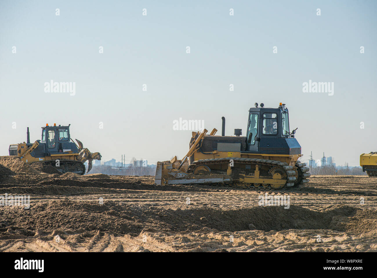Macchinari pesanti lavorando su autostrada sito in costruzione. Un bulldozer, dumper, compattatore per suoli e rullo vibrante Foto Stock