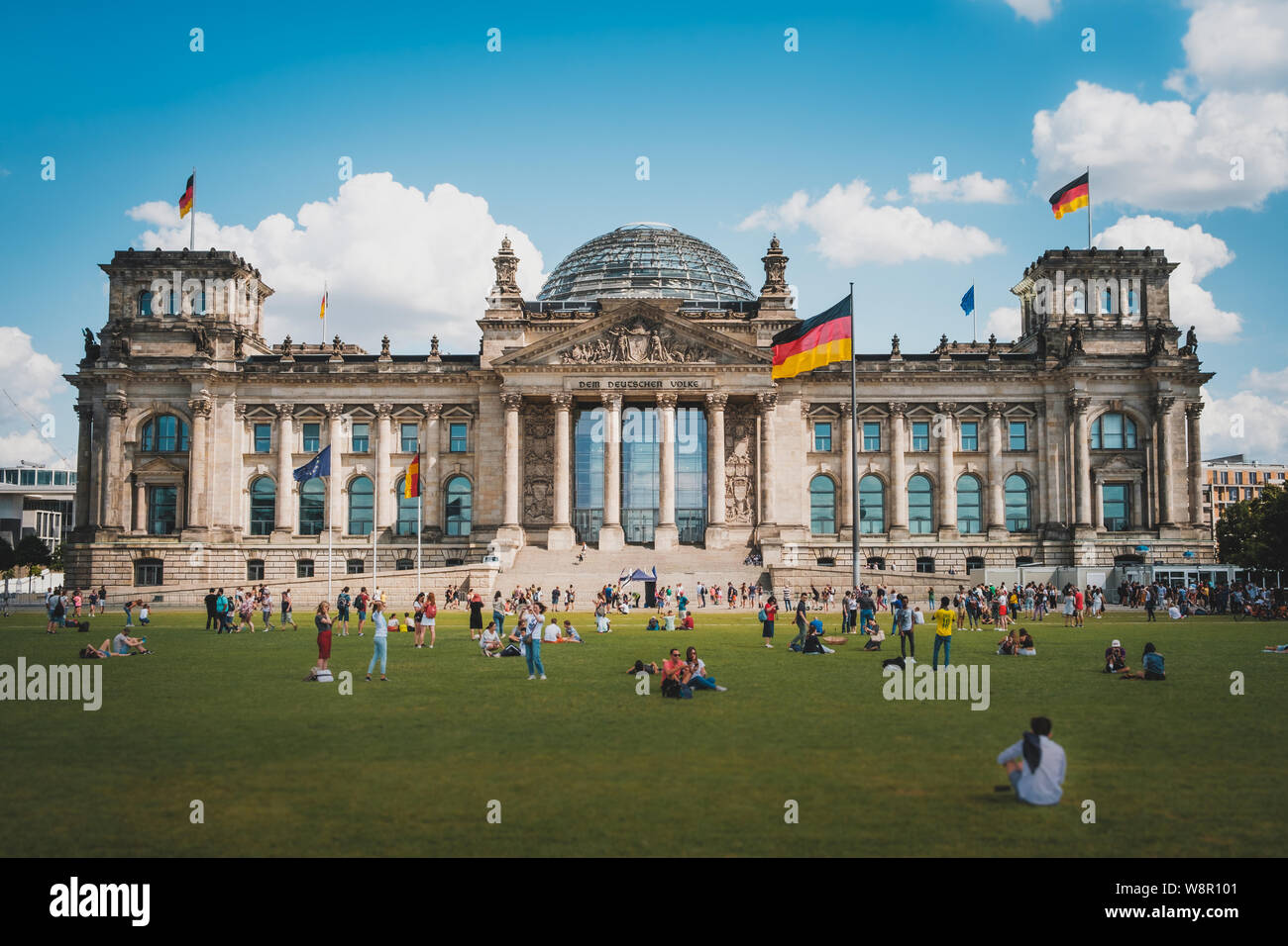 Berlino, Germania - Agosto, 2019: Molte persone sul prato di fronte al Reichstag (parlamento tedesco), un famoso punto di riferimento su una soleggiata giornata estiva Foto Stock