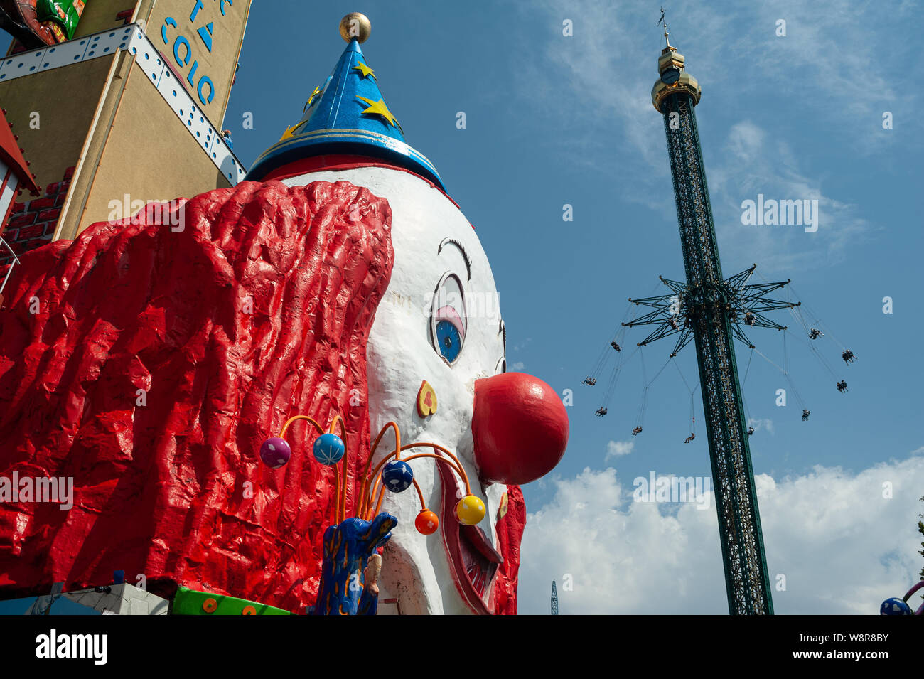 16.06.2019, Vienna, Austria, Europa - un gigante clown faccia e una chairoplane presso il parco divertimenti del Wiener Prater. Foto Stock