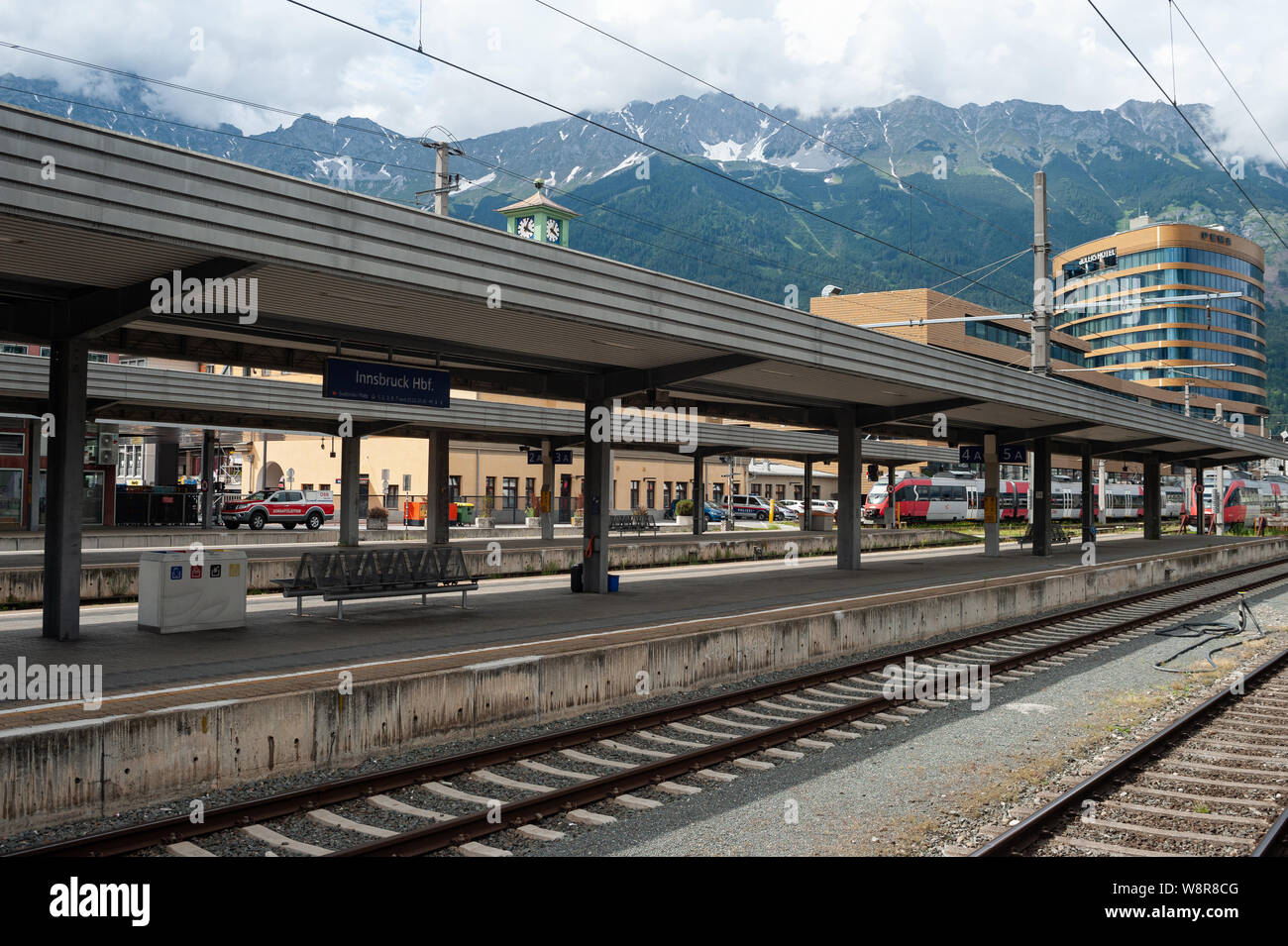 22.06.2019, Innsbruck, in Tirolo, Austria, Europa - Piattaforma e binari ferroviari presso la stazione ferroviaria centrale con le montagne come sfondo. Foto Stock
