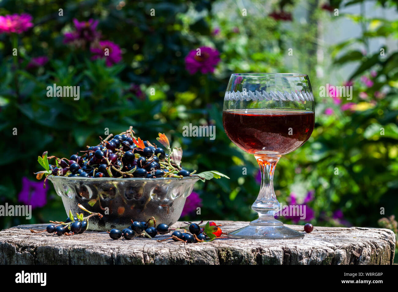 Vino di ribes nero con frutti di bosco in vetro avza da un vecchio tavolo in legno Foto Stock