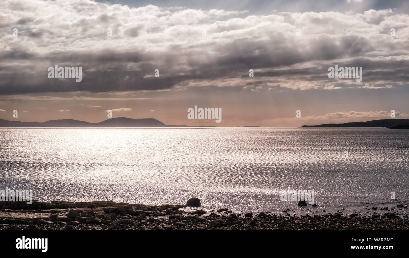 Di sera il sole filtra attraverso le nubi su Gair Loch e isole distanti nelle Highlands della Scozia Foto Stock