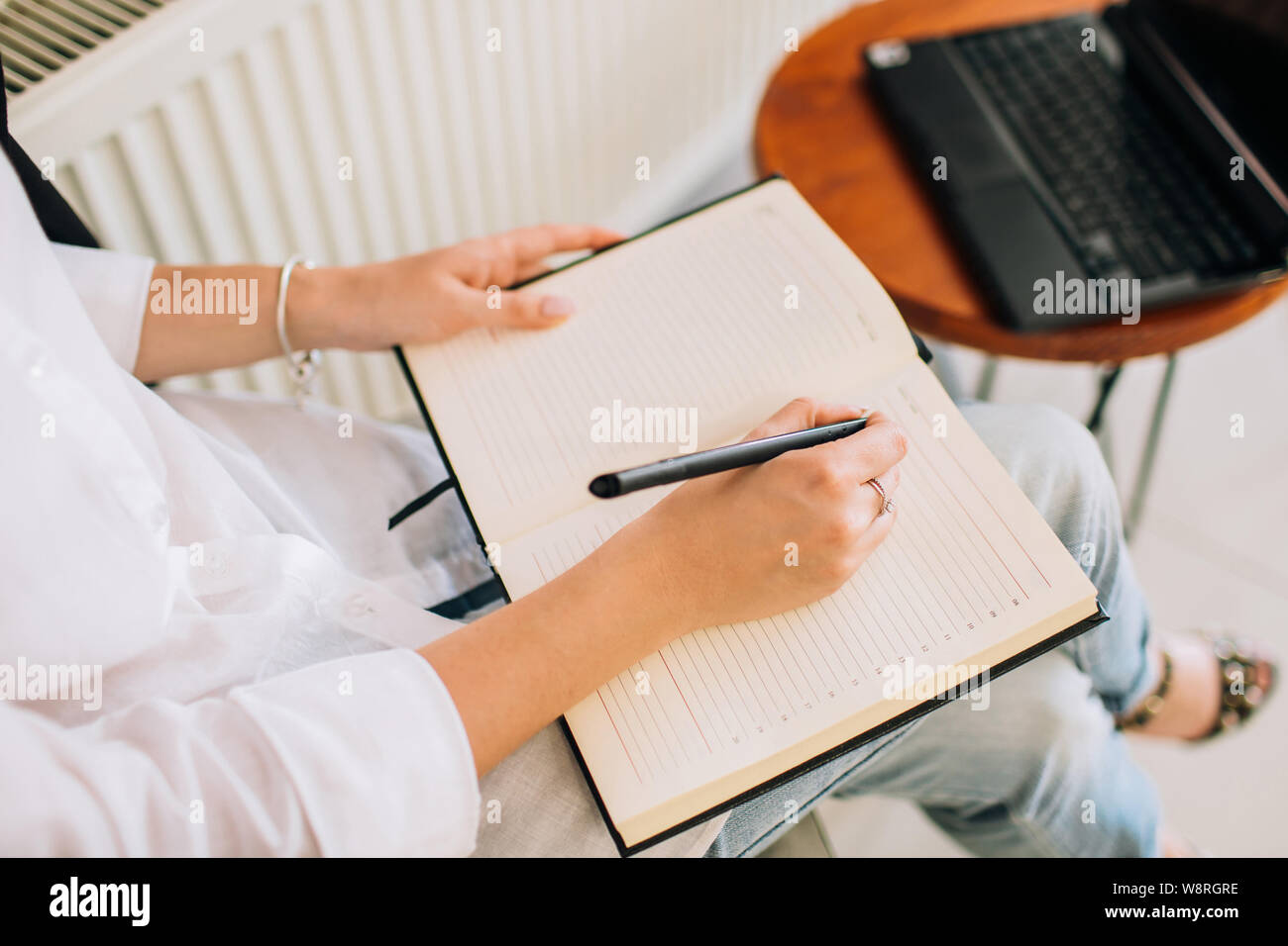 Mani femminili la scrittura in un blocco note, vista dall'alto. Imprenditrice lavorando un accogliente area di lavoro. Foto Stock