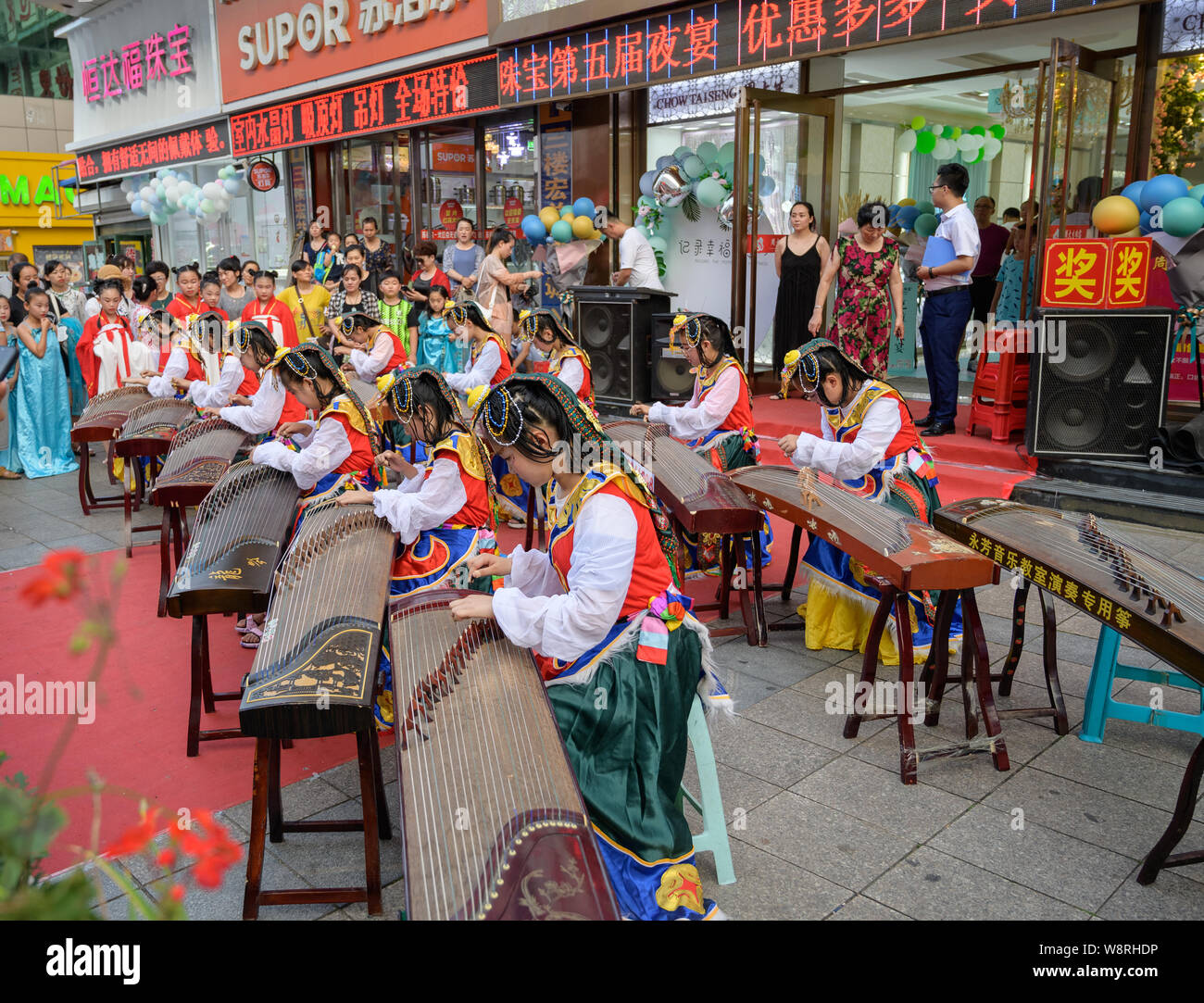 MISHAN, Cina - 28 luglio 2019: i bambini vestiti in cinese tradizionale costume cinese suona uno strumento musicale - GU Zheng. Foto Stock