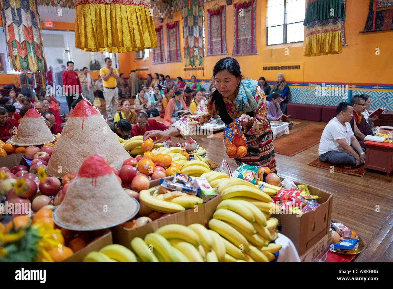 Una pia donna buddista offre cibo al Buddah. Presso lo Sherpa Kyidug tempio di Elmhurst, Queens, a New York. Foto Stock